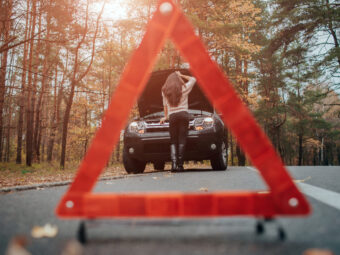 Auto assistance and insurance, troubles while traveling concept. Broken car and auto triangle on road, woman waiting for help